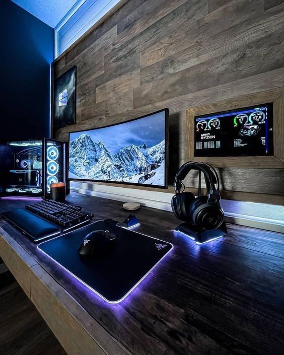 a rustic gaming space with a stained wood accent wall, a PC and lit up devices, some decor on the stained desk