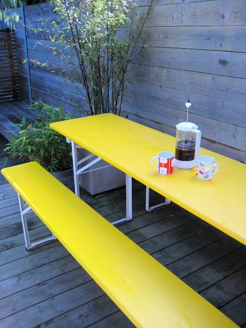a simple modern dining space with bold yellow table adn benches plus some greenery is cool and catchy space