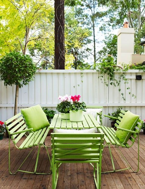 a simple modern terrace with a bright green table, benches and chairs, potted blooms and greenery is lively