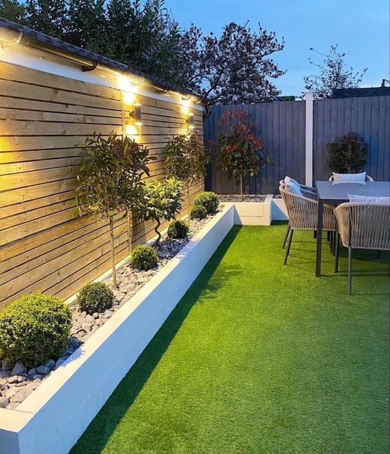 a small and cool modern garden with a green lawn, some shrubs, trees, a modern dining set plus lamps is amazing
