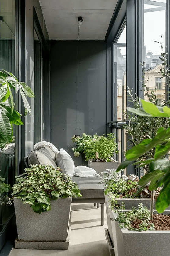 a small and laconic balcony with potted plants, a small grey loveseat and cool views is a lovely space to spend some time and relax