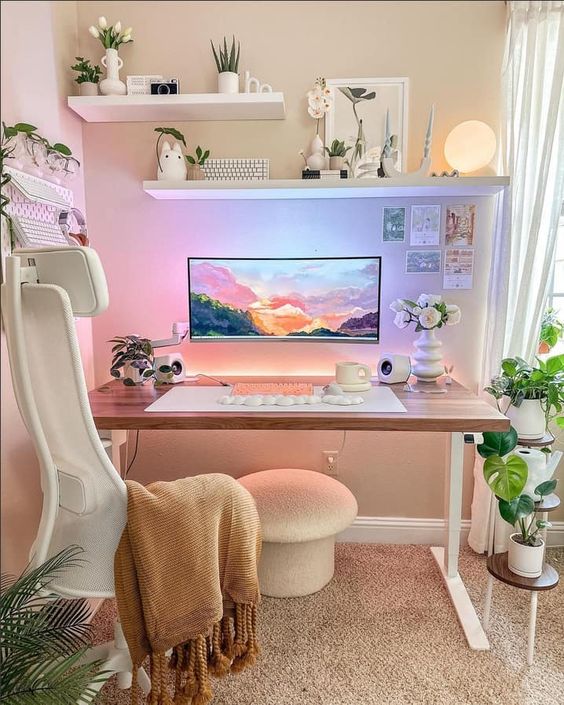 A small and lovely gaming desk setup with shelves, potted plants, a monitor on the wall, a white chair and a mushroom shaped stool