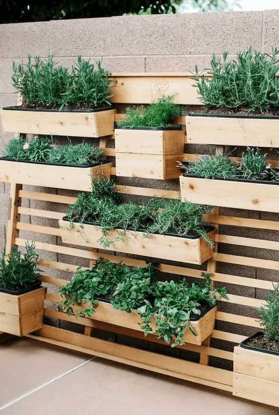 a small and smart wooden garden pf wooden planks, with wooden planters, greenery and herbs is a lovely idea for a modern rustic outdoor area