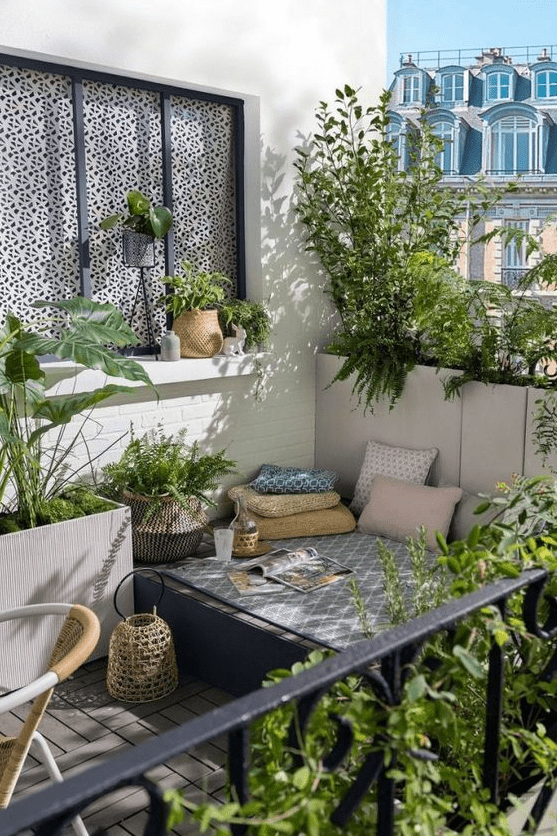 a small balcony with a daybed and bright pillows, potted greenery and a chair and some baskets is cool