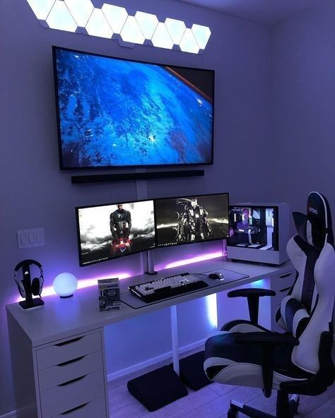 a small black and white gaming nook with some screens, a desk and a chair, some devices and lights on the wall