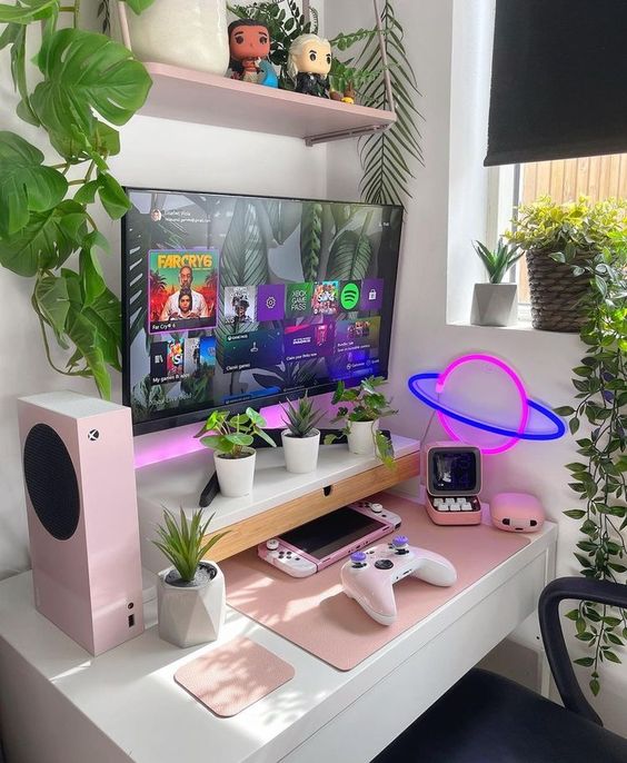 a small bold gaming desk setup with a desk, potted plants, a neon light, some pink stuff and decor is a cute corner