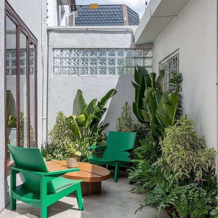 a small outdoor nook with greenery, green wooden chairs, a coffee table and some decor is chic and bold