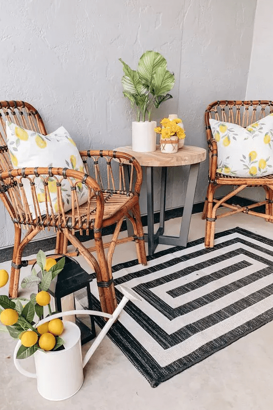 a small outdoor space with rattan chairs, a coffee table, a printed rug, a watering can with fake lemons for a bold touch