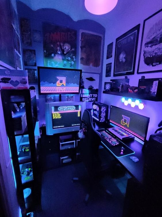 a small purple gaming nook with a desk, some screens and a PC, a shelving unit with decor and posters on the wall plus purple neon lights