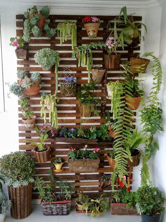 a stained vertical garden of wood, with various planters and baskets, with greenery and blooms is a cool idea for a balcony and not only