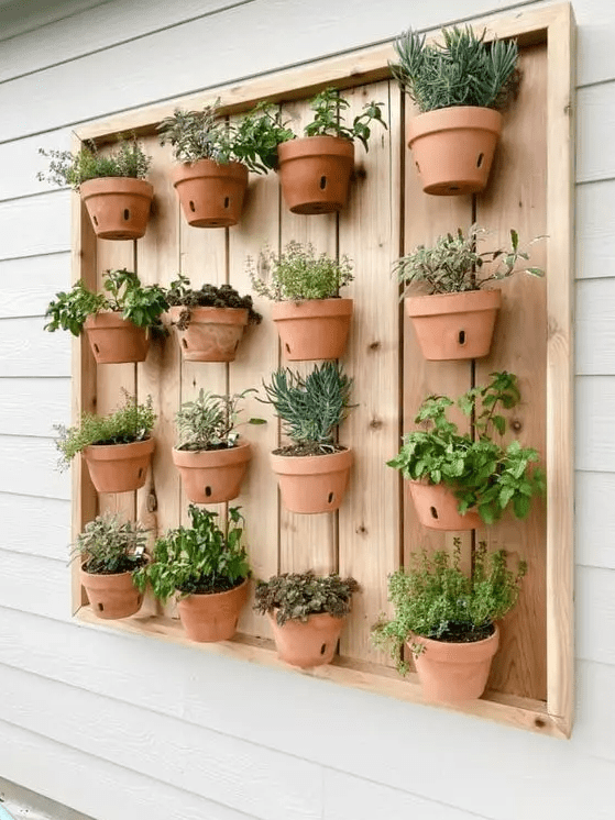 a stained wooden pallet with lots of terracotta planters and herbs is a lovely idea for a rustic space