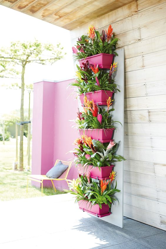 a stand with fuchsia planters and super bright blooms is a creative vertical garden that will easily fit many spaces