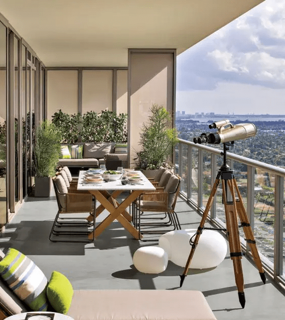 a stylish contemporary balcony with a sofa in the corner, greenery in pots, a dining space with a trestle table and metal chairs, a lounger is a lovely space