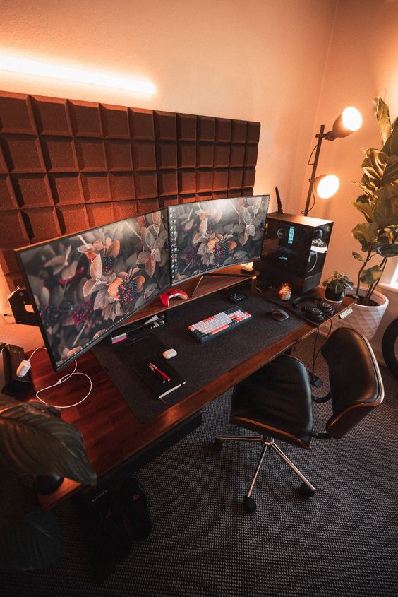 A stylish modern gaming space with sound proof panels, a desk, a chair, a couple of screens, a PC and floor lamps