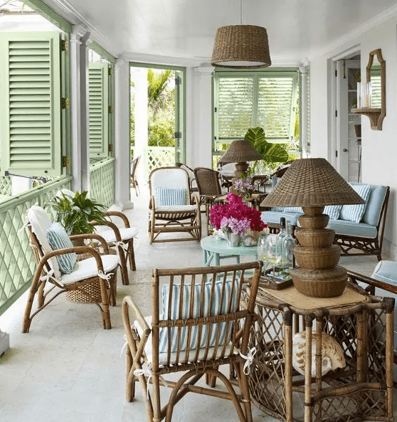 a stylish veranda with rattan chairs, a blue table and a sofa, a rattan table and a wicker lamp plus green shutters on the windows