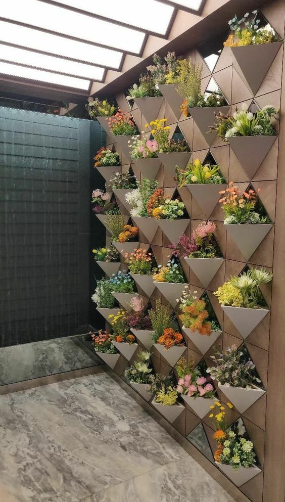 a super stylish geometric vertical garden with triangle planters, blooms and greenery is a cool idea for both indoors and outdoors