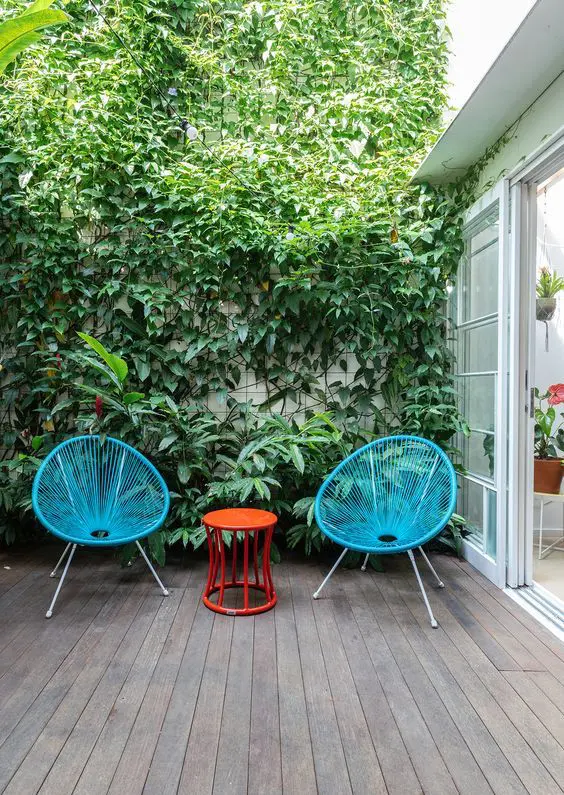 a terrace with a living wall, blue chairs, a red side table is laconic and colorful, looks very vivacious