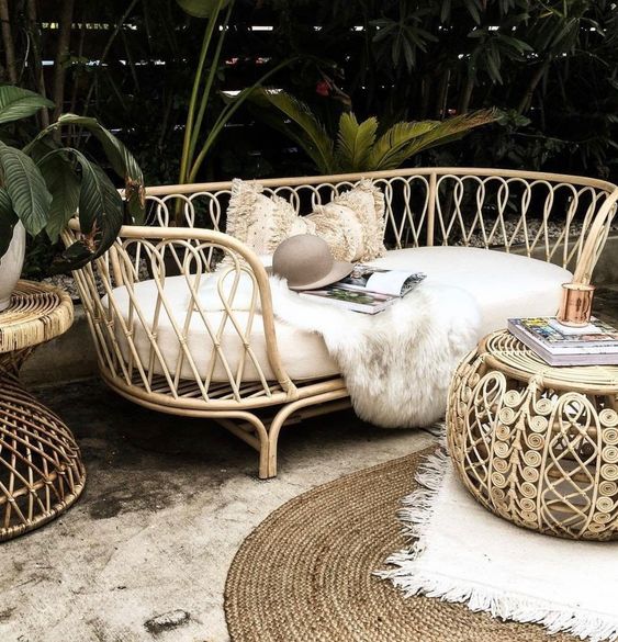 a tropical outdoor space with chic and bold rattan furniture, boho rugs and statement plants around