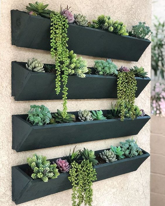 a vertical garden with dark planters and succulents is a super cool and catchy idea for any modern outdoor space