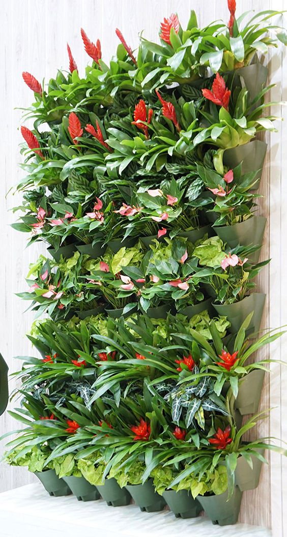 a vertical garden with green planters and bright plants is a super cool and bold idea for an outdoor space