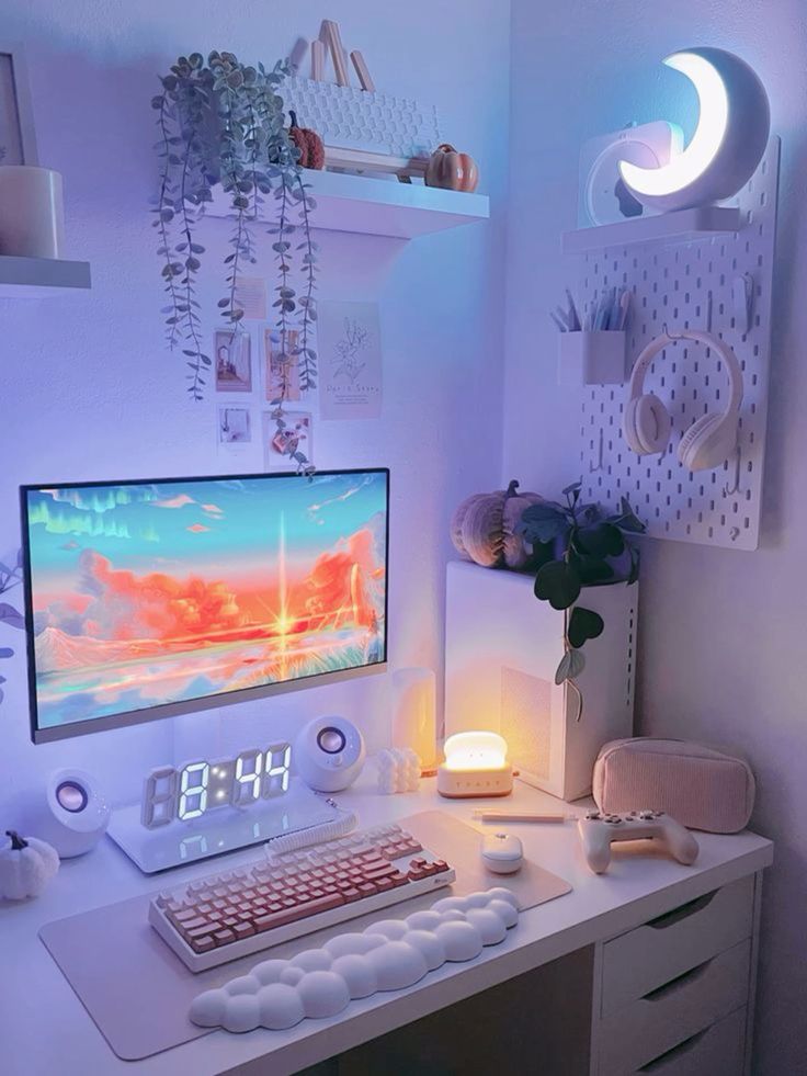 a white gaming desk setup with a desk, a lamp, a moon lamp, potted greenery, a board with decor