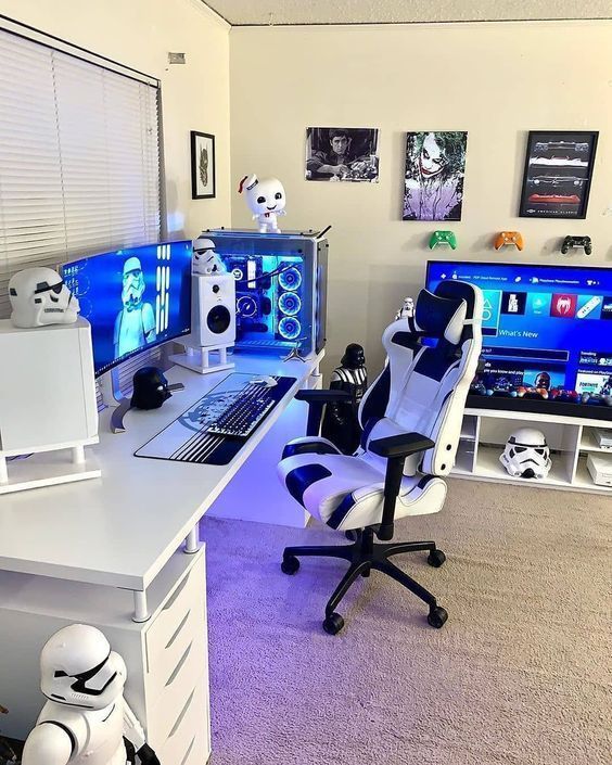 a white gaming space with a desk, a chair, a TV unit, some devices, a PC, a TV and Star Wars inspired figurines here and there