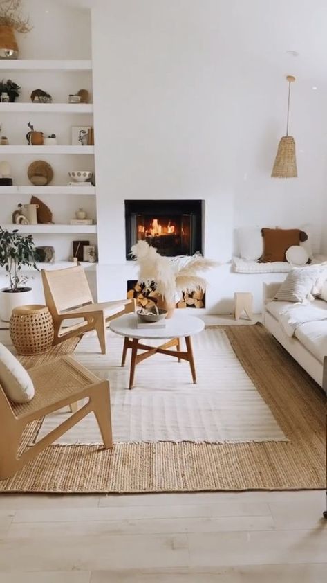 A white living room with a fireplace, a built in bench, a white sofa, cane chairs, built in shelves and a coffee table