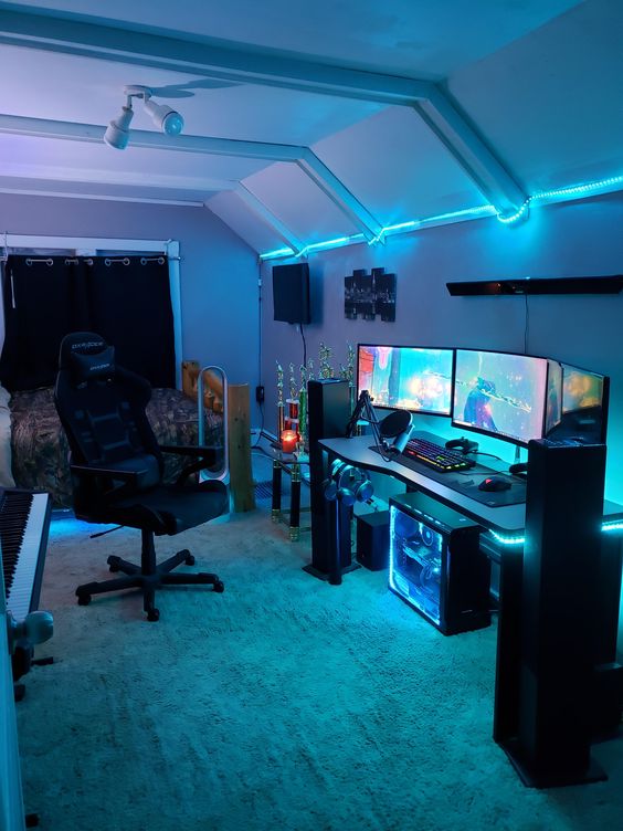an aqua blue gaming setup with a desk, some screens and lights and a black chair is always a good space to play a bit