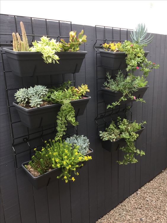 grids hanging on the wall with grey planters with succulents are a cool idea for an outdoor space or a balcony, they look stylish