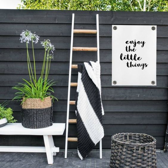 refresh your black fence with a white bench, a neutral ladder, some decor, blooms and greenery to make it look fresh