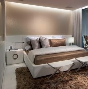 neutrals, tan and brown decor, built-in lights and touches of metal make up the small bedroom larger and very luxurious