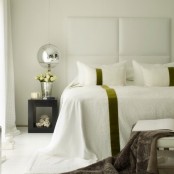 an oversized headboard with horizontal upholstered panels and mirror pendant lamps used for enlarging the space