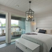 a neutral farmhouse bedroom with horizontal beadboards covering the walls and ceiling to visually expand the bedroom