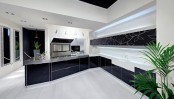 a sleek contemporary black and white kitchen with black cabinets and a floral one, white countertops and white pendant lamps