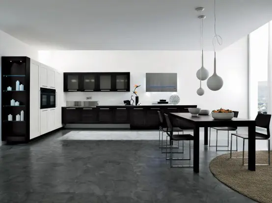 A contemporary black and white kitchen with black cabinets, a white storage unit with built in appliances and a dining zone with black furniture