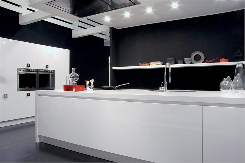 A contemporary black and white kitchen with black walls, sleek white cabinets and a kitchen island, built in appliances and lights all over