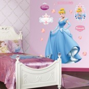 a Disney princess themed kids’ room done in pink, with art on the wlal and a bed done with pink bedding