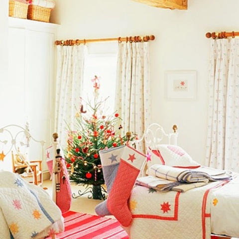 a Christmas bedroom with a Christmas tree and colorful pompoms, bright bedding and star printed blankets