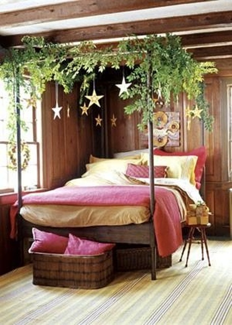a red and white Christmas bedding set with greenery on the bed frame and stars hanging down for a Christmas feel