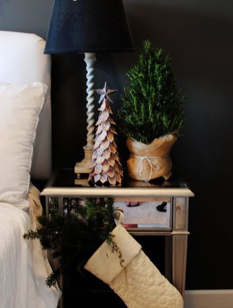 a white stocking with evergreens, a mini tree in burlap and a tree made of cardboard to bring a holiday feel