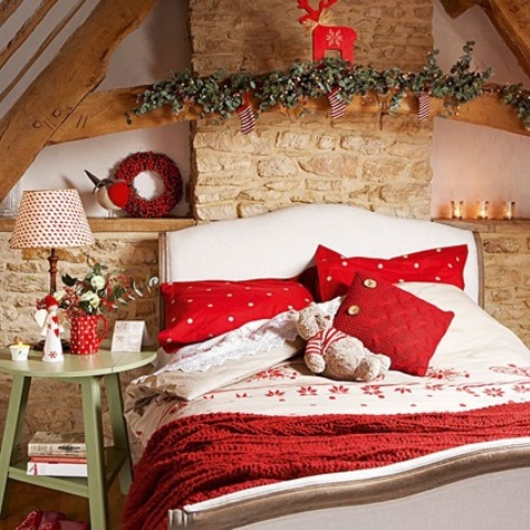 a cozy and small Christmas bedroom with a stone wall, evergreens, a red deer and a red wreath, chic red and white bedding and printed lamps