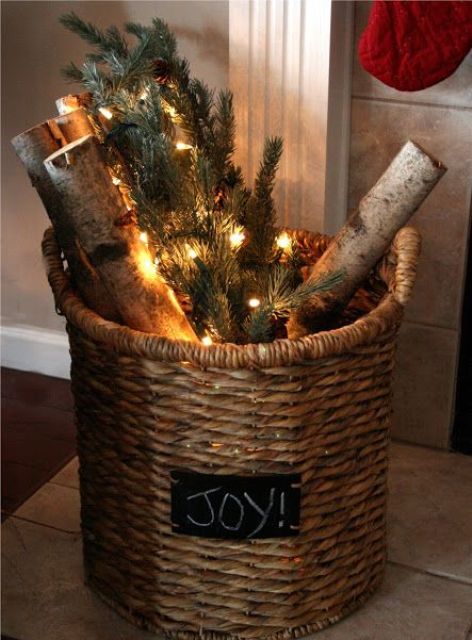 a basket with a chalkboard sign, firewood, evergreens and lights is a pretty rustic decor idea for Christmas, even if you don't have a fireplace
