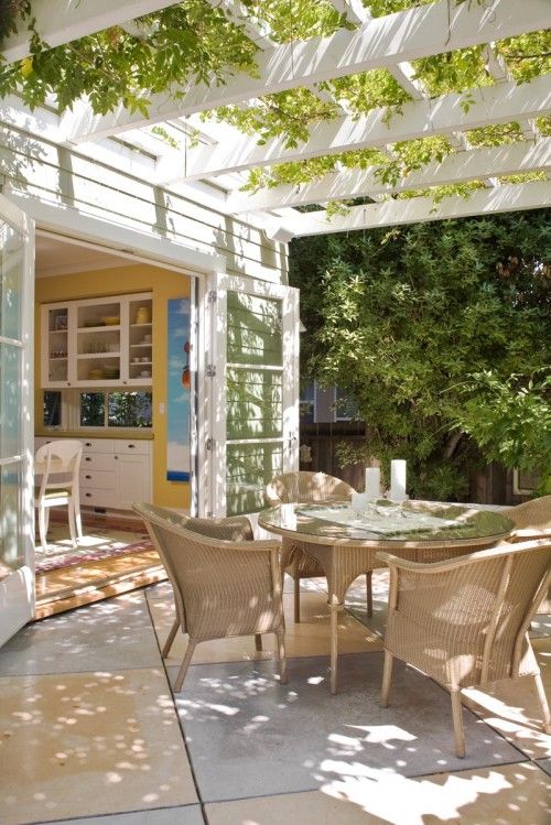 A neutral eat in kitchen with doors to the garden that can be opened to eat outdoors, under a small roof with greenery