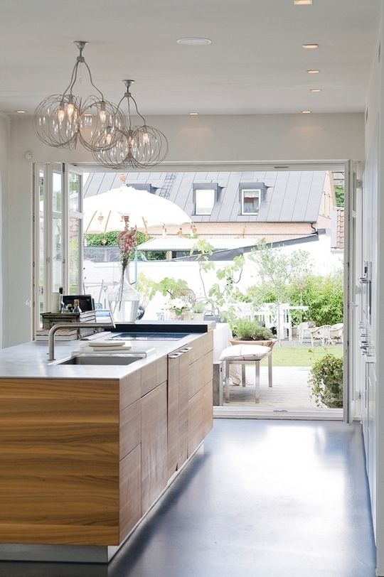 a modern kitchen with a folding glass wall that can be opened to get access to an outdoor dining zone and enjoy fresh air