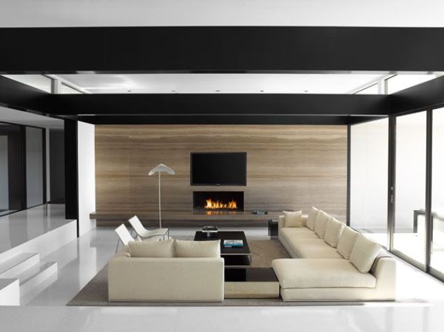 A minimalist living room with a conversation pit, contemporary furniture, a fireplace and a dark framed ceiling