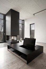 a minimalist living room with large windows for views and natural light, a black hearth and a black coffee table with a hidden TV
