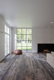a minimalist liivng room with a fireplace, a white sofa and large windows that offer much natural light