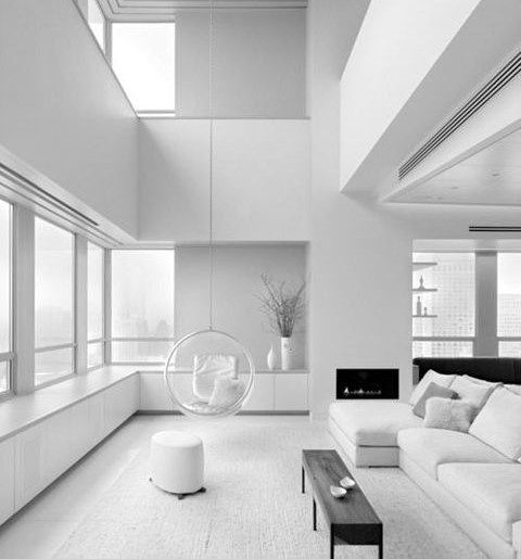 A pure white minimalist living room with a built in fireplace, windows, white and black furniture
