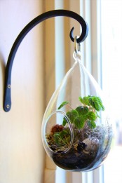 a drop terrarium with greenery, blooms and a fake nest and a faux egg is a pretty decoration to rock for spring