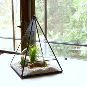 a triangle terrarium with sand, faux grass and pebbles is an elegant decoration that doesn’t require any care